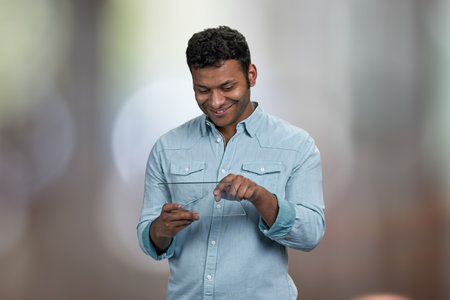 Smiling young man using transparent digital tablet. Abstract bokeh background.の写真素材