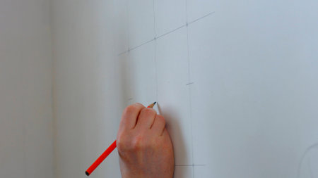 Builder draws marking on the wall. Worker making measurements.の写真素材