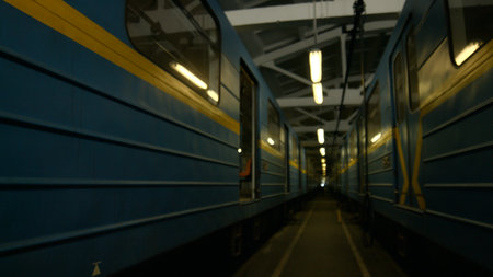 A modern metro train stands in the depot. Train cars are lined up along the track, technicians are...