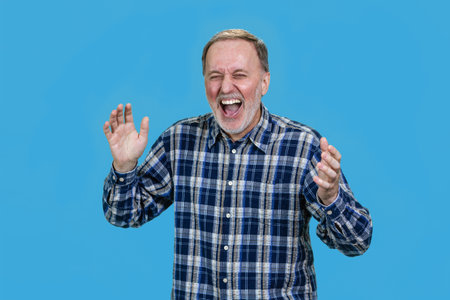 Senior mature businessman is laughing hard out loud. Isolated on vivid blue.の写真素材