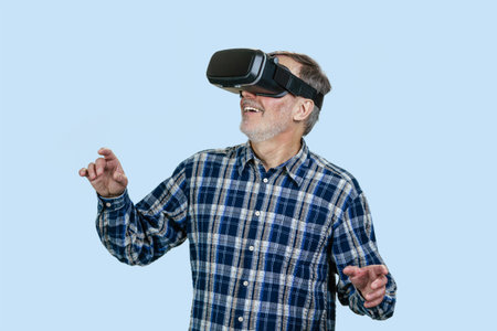 Happy senior man experiencing virtual reality in headset. Isolated on blue.