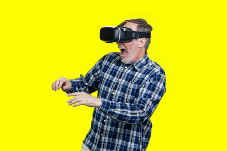 Portrait of scared senior man in vr headset. Isolated on yellow.の写真素材
