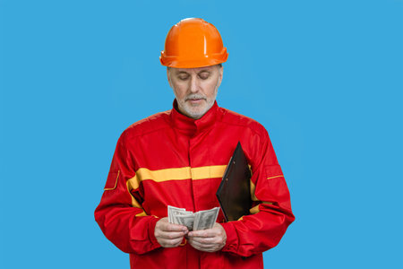 Portrait of construction worker is counting money. Isolated on blue.の写真素材