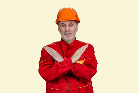Handsome old caucasian worker shows the sign of prohibition. Isolated on white.の写真素材