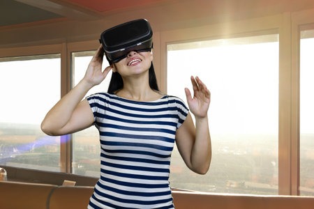 Portrait of a young brunette woman wearing headset. Indoor windows with sunlight on the background.