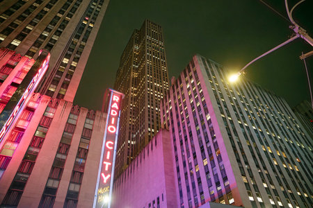 Vibrant neon signs light up Radio City as crowds stroll the bustling streets of Manhattan....