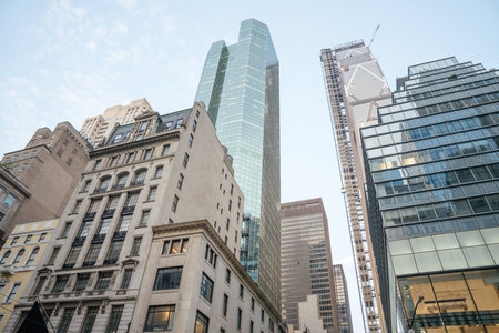 Tall modern skyscrapers with glass facades rise above older, ornate buildings in Midtown Manhattan. The contrast between new architecture and historic design captures the essence of New Yorks evolving skyline.の写真素材