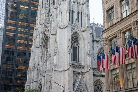 A close-up view of the ornate facade of St. Patricks Cathedral on 5th Avenue in Manhattan. American flags hang proudly from the building opposite, highlighting New Yorks patriotic and architectural charm.の写真素材