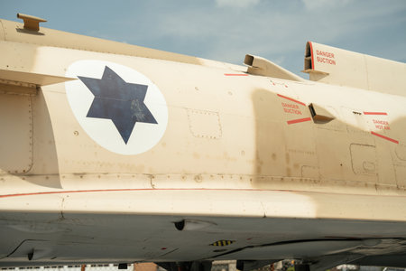 Close-up of a beige Israeli military aircraft fuselage showing a blue star emblem. Red danger warnings, suction vents, and hot air exhausts are visible on the surface.の写真素材