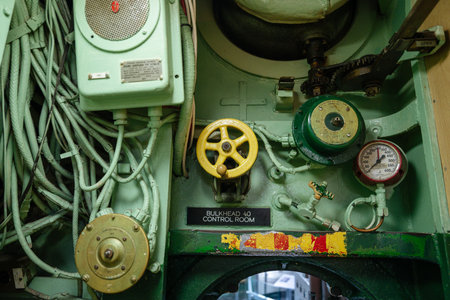 A detailed view of submarine machinery shows yellow and green control valves, a pressure gauge, and...
