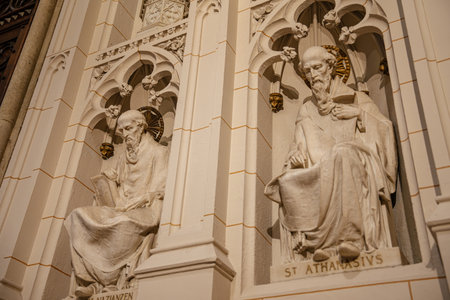 The image captures detailed marble sculptures of Saint Athanasius and Saint Gregory of Nazianzus in an ornate church wall niche. The figures are seated with halos and books, surrounded by Gothic architectural elements.の写真素材
