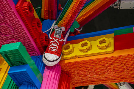 A small mouse sits inside a bright red sneaker on top of a colorful rainbow structure made entirely of bricks. The intricate build features vivid colors and playful design elements.の写真素材
