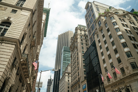 An upward view captures American flags on historic stone buildings along Fifth Avenue in Midtown...