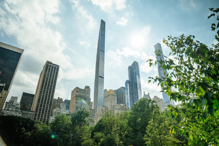 Tall skyscrapers rise above the lush greenery of Central Park on a bright sunny day in New York...