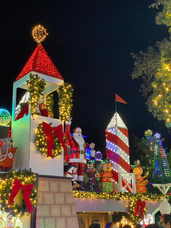 Santa Claus stands between glowing red towers surrounded by Christmas decorations and lights. The festive outdoor installation creates a joyful holiday atmosphere.の写真素材