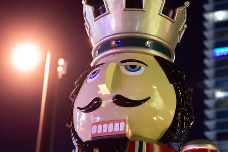 A glossy nutcracker head with a jeweled crown shines in streetlights. The festive statue shows bright Christmas colors in the city.の写真素材
