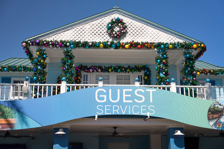 Orlando, Florida, USA - 11.15.2024: A guest services building is decorated with colorful Christmas garlands and wreaths. Bright ornaments and lights create a festive holiday scene under a sunny blue sky.のeditorial素材
