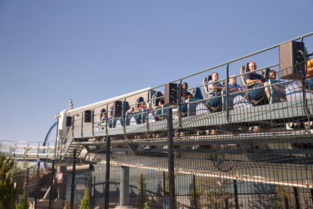 Orlando, Florida, USA - 11.15.2024: Riders sit in a coaster train on an elevated dispatch platform. Bright sunlight and metal rails highlight the attraction.のeditorial素材