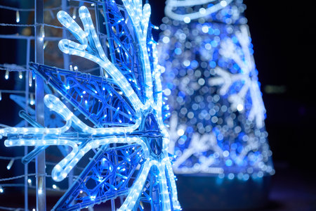 A bright LED snowflake shines with blue and white holiday lights. Soft bokeh and twinkle effects create a magical winter mood.の写真素材