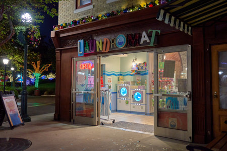 Orlando, Florida, USA - 11.15.2024: A bright laundromat storefront stands open at night with garland and lights. Washers, racks, and colorful displays invite shoppers inside.のeditorial素材