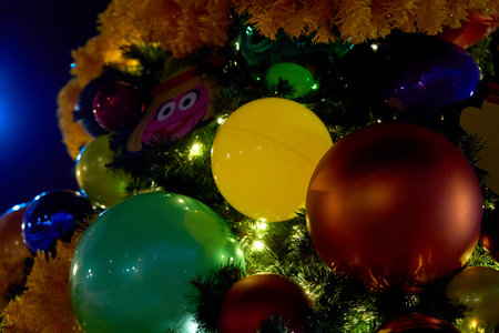 Orlando, Florida, USA - 11.15.2024: Large glossy ornaments and yellow tinsel wrap a Christmas tree with sparkling lights. A close macro view highlights texture and color.のeditorial素材