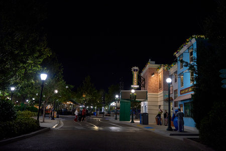 Orlando, Florida, USA - 11.15.2024: Wide evening street with glowing lampposts, trees, and decorated buildings. People walk past colorful storefronts under holiday garlands.のeditorial素材
