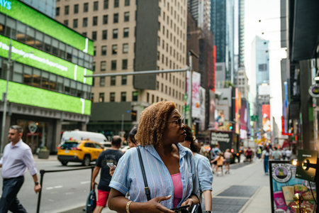 New York City, New York, USA - 08.01.2024: People walk along a busy sidewalk in Times Square, New York City, with taxis, traffic, and colorful billboards in the background. The image captures everyday life, motion, and diversity in the heart of Manhattan.のeditorial素材