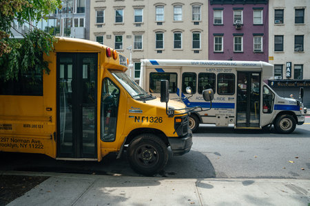 New York City, New York, USA - 08.02.2024: A yellow school bus is parked beside a white city shuttle...