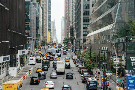 New York City, New York, USA - 08.02.2024: Midtown Manhattan traffic flows between modern glass skyscrapers and busy sidewalks in New York City. Yellow taxis and private vehicles create a dynamic urban transportation scene.のeditorial素材