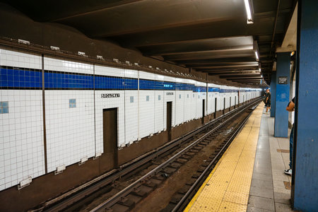 New York City subway platform with Broadway tiled wall and railway tracks in Manhattan. Underground...
