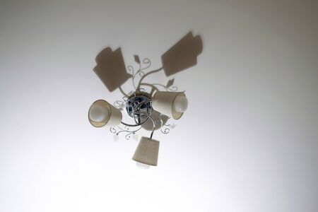 Beautiful shadow from the chandelier on the ceiling in the room, three lamps
