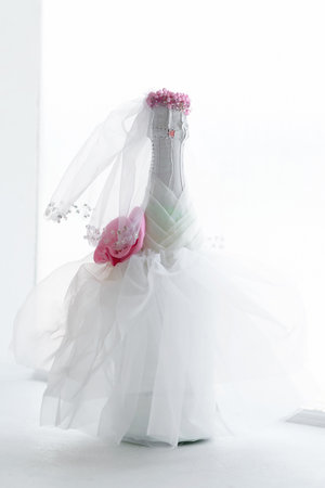Wedding bottle of champagne decorated in the bride's dress stands at the window on the windowsill. Wedding compositionの写真素材
