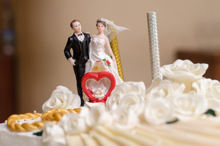 Statuettes of the bride and groom are on the wedding cake, close-upの写真素材