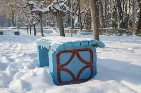 Blue bench in the Park covered with snow in winter landscapeの写真素材