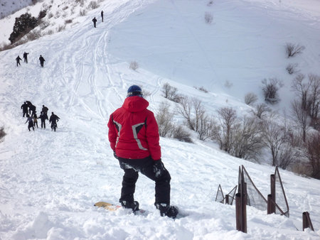 Guy in a red jacket stands on a snowboard on a mountain top in the snow, view from the backのeditorial素材