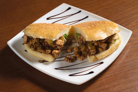 Pulled sandwich with pieces of fried chicken meat and pickles on a plateの写真素材