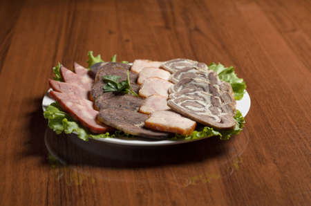 Meat delicacies slicing, cold cuts, beef meat, smoked turkey, horse meat in a white plate on the...