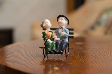 Statuette of elderly people couple man in suit and hat and woman in dress sitting on benchの写真素材