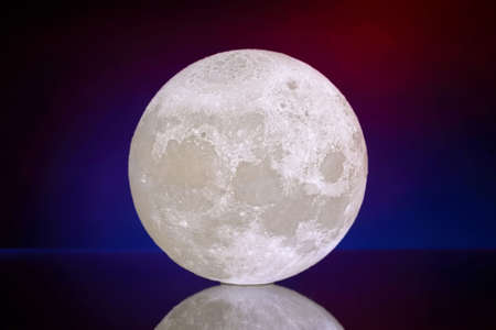 Artificial full moon close-up lamp on a blue red dark backgroundの写真素材