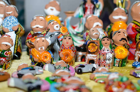 Traditional ceramic figurines of happy Uzbek men and women in national clothes with bread in handsの写真素材