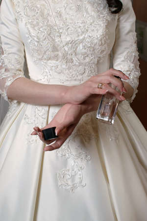 Bride in a white dress holds an open perfume bottle in her handsの写真素材