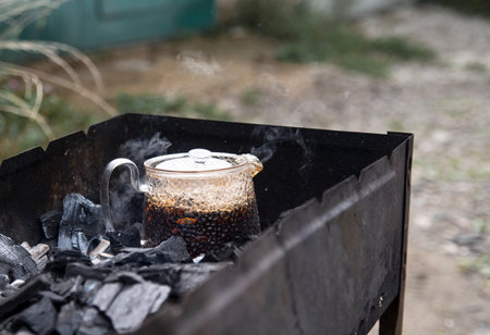 Tea in a glass teapot is brewed in a charcoal grill