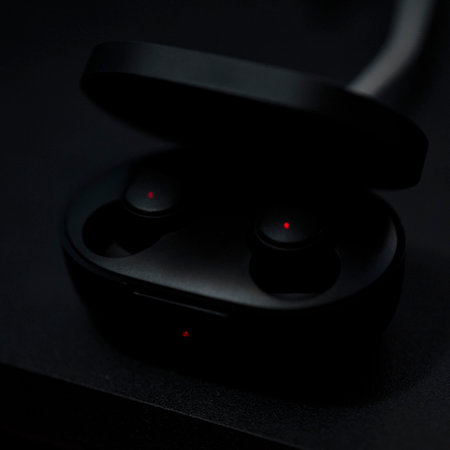 Black headphones are charging in the case. Charging indicators are glowing red. Macro shoot.の写真素材