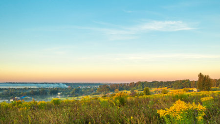 View of the outskirts of Oryol in the morning at dawn in the fog, field herbs in the foreground, small houses, fields, forests. Russian provincial landscape.の写真素材