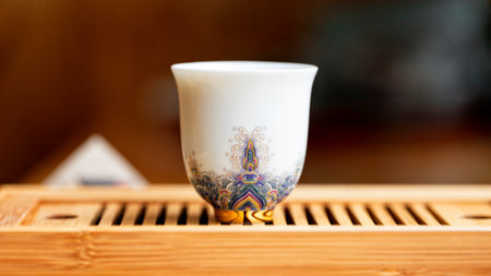 A chic Chinese tea bowl, white with the pattern of all the colours of the rainbow and a golden bottom, a macro image with a blurred background.の写真素材
