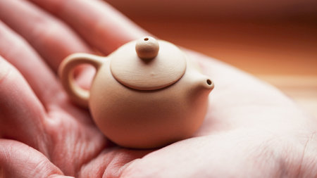 A very small clay yixing teapot on an open palm. Macro photography in soft pastel colors.の写真素材