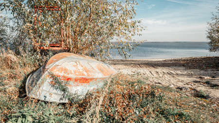 A rusty overturned boat on the riverbank.の写真素材