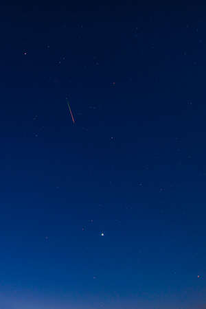 Bright red-green meteor of Perseid flow in the night sky
