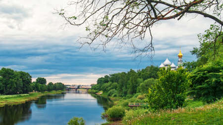 A natural landscape of the Vologda River with greenery and churches on the bank