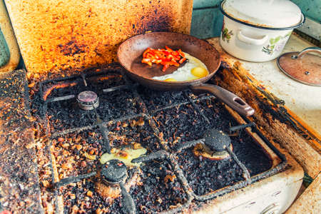 Dirty stove and broken chicken egg on it, pan with fried egg and sweet pepperの写真素材
